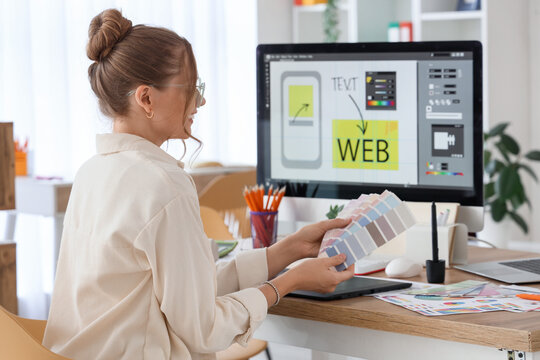 Female web designer with color palettes at table in office