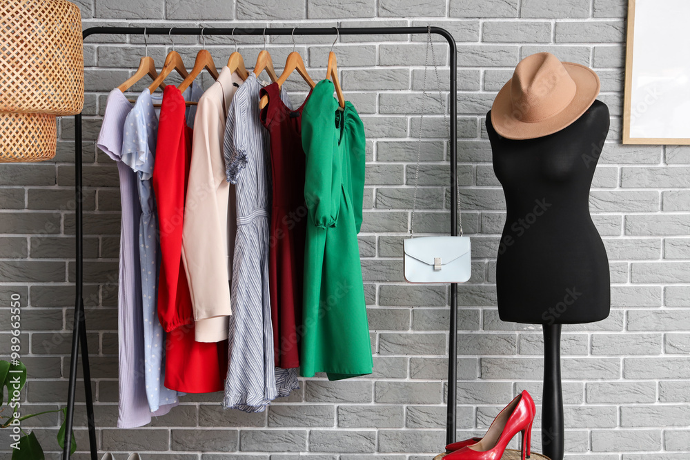 Mannequin with hat and clothes rack near grey brick wall in dressing room
