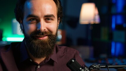 Wall Mural - Portrait of content creator using high tech quality mic in studio to do ASMR video, discussing with viewers. Smiling man using professional microphone to record podcast, camera A close up