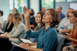 © SejutaCahaya - A woman raises her hand to ask a question during a business meeting or conference.