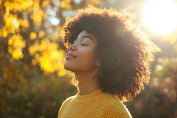 Wall Mural - Afro woman wearing yellow knitted sweatshirt in autumn park at sunny day