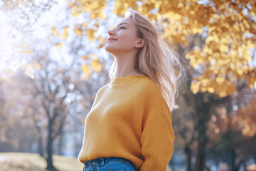 Wall Mural - Caucasian woman wearing yellow knitted sweatshirt in autumn park at sunny day