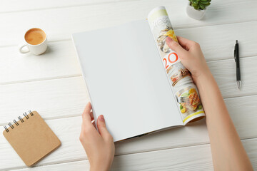 Wall Mural - Woman reading magazine at white wooden table, closeup. Mockup for design