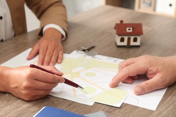 Wall Mural - Real estate agent working with client at wooden table, closeup