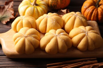 Raw pumpkin shaped buns and ingredients on wooden table, closeup