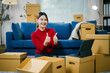 © Parichat - Young woman is smiling and giving thumbs up while unpacking boxes in her new apartment. She is happy with the service provided by the moving company