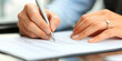 © Jaruwan photo - Close up of persons hands signing document with pen, showcasing sense of commitment and professionalism. elegant ring adds personal touch to moment
