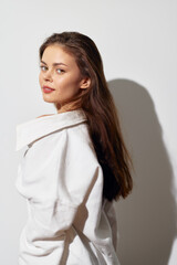 Wall Mural - Portrait of a young woman with long hair wearing a white shirt against a plain light background, showcasing natural beauty and confidence in a minimalist setting