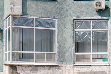 The windows are covered with plastic and the building is grey