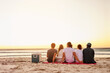 © StarDweller/peopleimages.com - Back, friends and relax for picnic at beach with sunset view, social gathering and alcohol basket of holiday break. People, rest and reunion together with vacation, bonding and summer travel by ocean