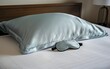 © Jason - Silk pillow and sleep mask on bed. Sleep care routine concept