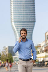 Wall Mural - Young businessman talking on the smartphone by the riverside