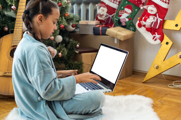 Wall Mural - Christmas distance learning online education. Schoolgirl studying at home with laptop notebook and doing school homework