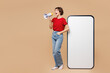© ViDi Studio - Full body young woman she wear red t-shirt casual clothes big huge blank screen mobile cell phone smartphone with area scream in megaphone isolated on plain pastel beige background. Lifestyle concept.