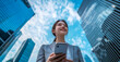 © Azazul - A young businesswoman smiles at her phone while standing in the bustling city center.