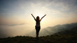 © panophotograph - Silhouette of woman stretching arms to sky on hilltop sun rising misty valley below serenity