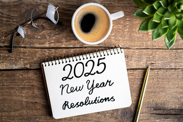 Wall Mural - New year resolutions 2025 on desk. 2025 goals list with notebook, coffee cup, plant on wooden table. Resolutions, plan, goals, action, checklist, idea concept. New Year 2025 resolutions. Copy space