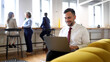© PeopleVideos - Young businessman working on his laptop at the company's lobby