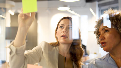 Two businesswomen brainstorming while making a business plan at their company