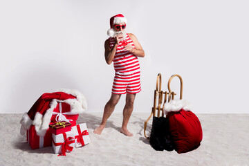 Canvas Print - Photo of funny santa claus dressed red striped swimsuit sunglass drink coktail summer beach isolated on white sandy background