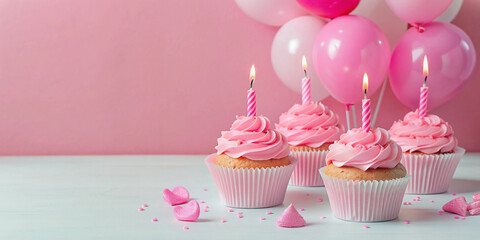  Pink frosted birthday cupcakes with lit candles, surrounded by pink and gold star decorations and golden confetti on a pink background, ready for celebration.