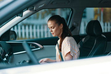 Wall Mural - Woman sitting in a car, looking thoughtful, in a modern vehicle interior with a blurred background, capturing a moment of introspection and calmness while driving