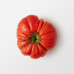 Wall Mural - A plump, vibrant red heirloom tomato, glistening with fresh water droplets, juicy and rich flavor