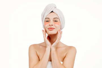 Wall Mural - A beautiful woman with blue eyes against a white background, wearing under-eye patches and a towel on her head. This image highlights self-care and the pursuit of a fresh, healthy appearance.