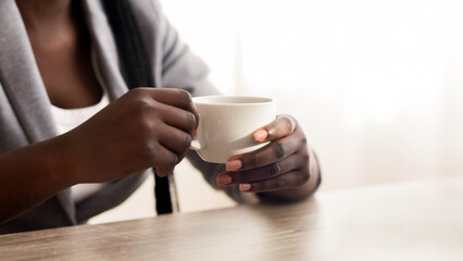 Poster - Unrecognizable afro businesswoman drinking coffee and using laptop in office, crop