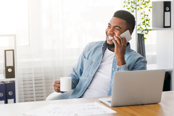 Poster - Handsome black ceo talking on phone and drinking coffee while sitting at workplace in office, copy space