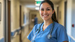 © Anastasia - A smiling healthcare professional wearing scrubs stands confidently in a hospital corridor, radiating warmth and dedication to patient care