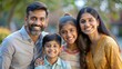 © N7 - A smiling Indian family of four posing together in a park, showcasing happiness and togetherness.