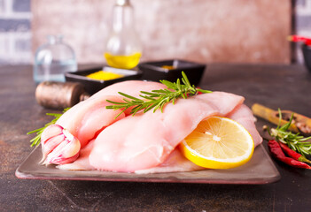 Wall Mural - Raw chicken breast or fillet with salt, pepper and fresh herbs on a plate on dark background. Healthy food. Top view, copy space