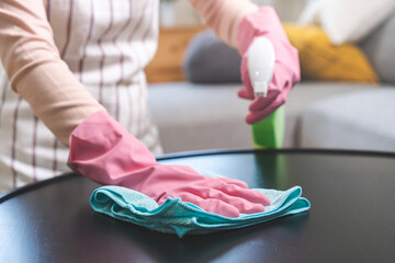 Wall Mural - Cleanliness asian young woman working chore cleaning on table at home, hand wearing glove using rag rub remove dust with spray bottle. Household hygiene clean up, cleaner, equipment tool for cleaning