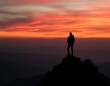 © TheseusStock - A lone hiker stands on the edge of a mountain peak, silhouetted against the fiery orange and pink hues of a sunset sky.