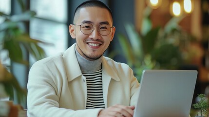 Young man with glasses works on a laptop in a cozy cafe filled with plants during the afternoon