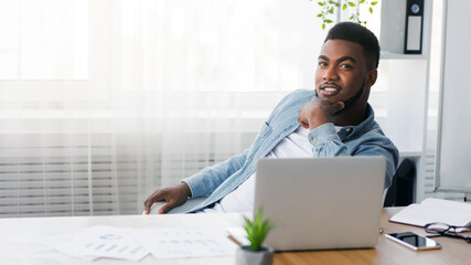 Poster - My first business. Portrait of young african american entrepreneur sitting at workplace in his own office.