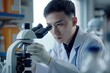 © Joaquin Corbalan - Chinese male doctor in a white coat examining samples under a microscope in a bright laboratory setting during the day