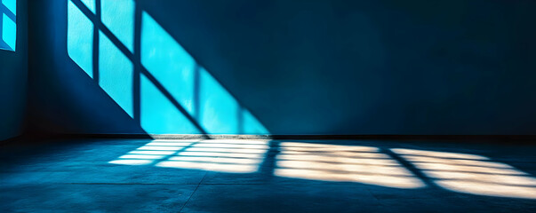 Wall Mural - Sunlight streams through a window casting shadows on a blue wall in an empty room