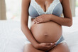 © Sanc/peopleimages.com - Pregnancy, stomach and hands of woman on bed for love, prenatal care and maternity. Pregnant belly, home and person in underwear in bedroom for rest, relax and calm for health, wellness and fertility