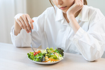 Diet in bored face, unhappy beautiful asian young woman, girl on dieting, holding fork at tomato on salad plate, dislike or tired with eat fresh vegetables. Nutrition of clean, healthy food good taste