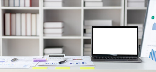 Work desk in office with documents and laptop on table.