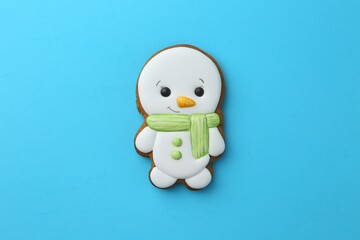 Wall Mural - Tasty Christmas cookie in shape of snowman on light blue background, top view