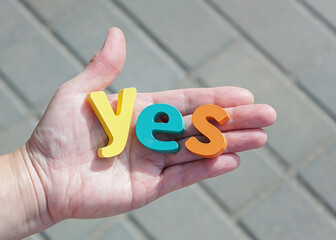 Human palm with word yes on gray background.