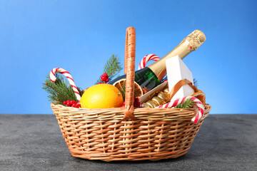 Wall Mural - Wicker gift basket with sparkling wine and Christmas decor on grey textured table against light blue background