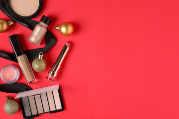 Wall Mural - Flat lay composition with makeup products and Christmas decor on red background, space for text