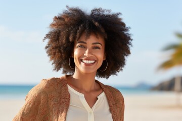 Wall Mural - Portrait of a grinning afro-american woman in her 40s wearing a chic cardigan in sandy beach background