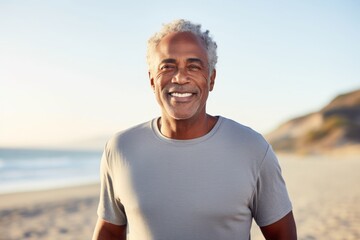 Wall Mural - Portrait of a happy afro-american man in his 60s sporting a long-sleeved thermal undershirt over sandy beach background