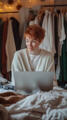 Wall Mural - Cozy home office setup: redhead in white sweater works on laptop surrounded by soft fabrics and warm lighting, creating a comfortable workspace.