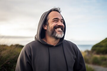 Canvas Print - Portrait of a grinning man in his 40s sporting a comfortable hoodie in serene seaside background